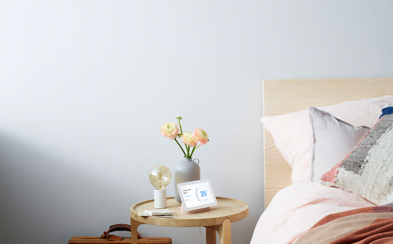 A Google Nest Hub smart display on a bedroom nighttable.