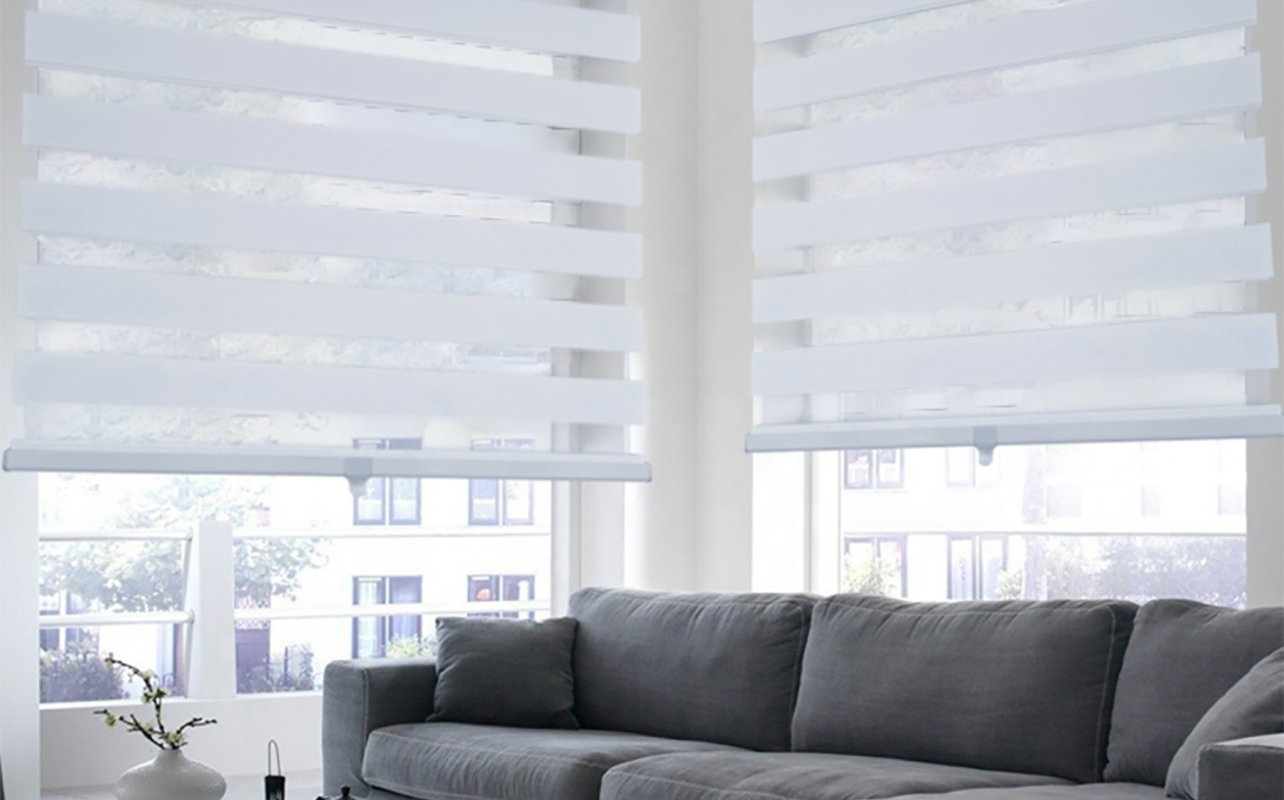 Ity Olivia Stone shades on a window by a couch in a living room.