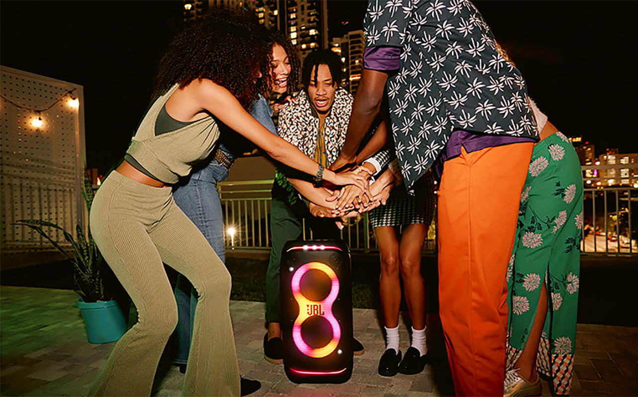 People standing around a JBL PartyBox speaker outside.