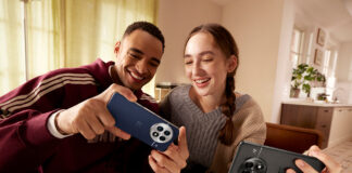 A young man and woman looking at OnePlus 13 phones and laughing.