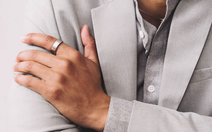 A man's hand folded over his chest wearing the Oura Ring 3.
