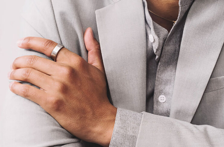 A man's hand folded over his chest wearing the Oura Ring 3.