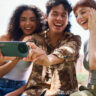 Three young students with the TCL 60XE smartphone taking a selfie.