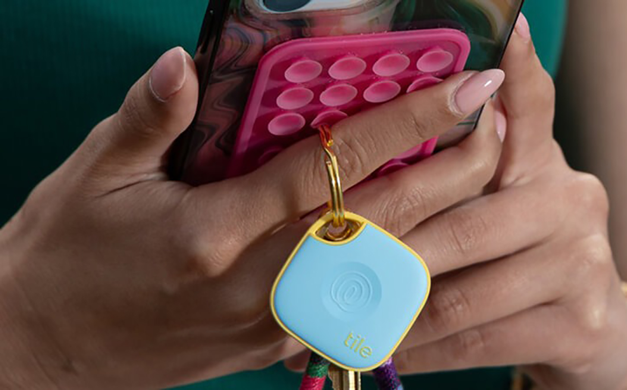 Hands holding a phone with the Tile Mate attached to it.