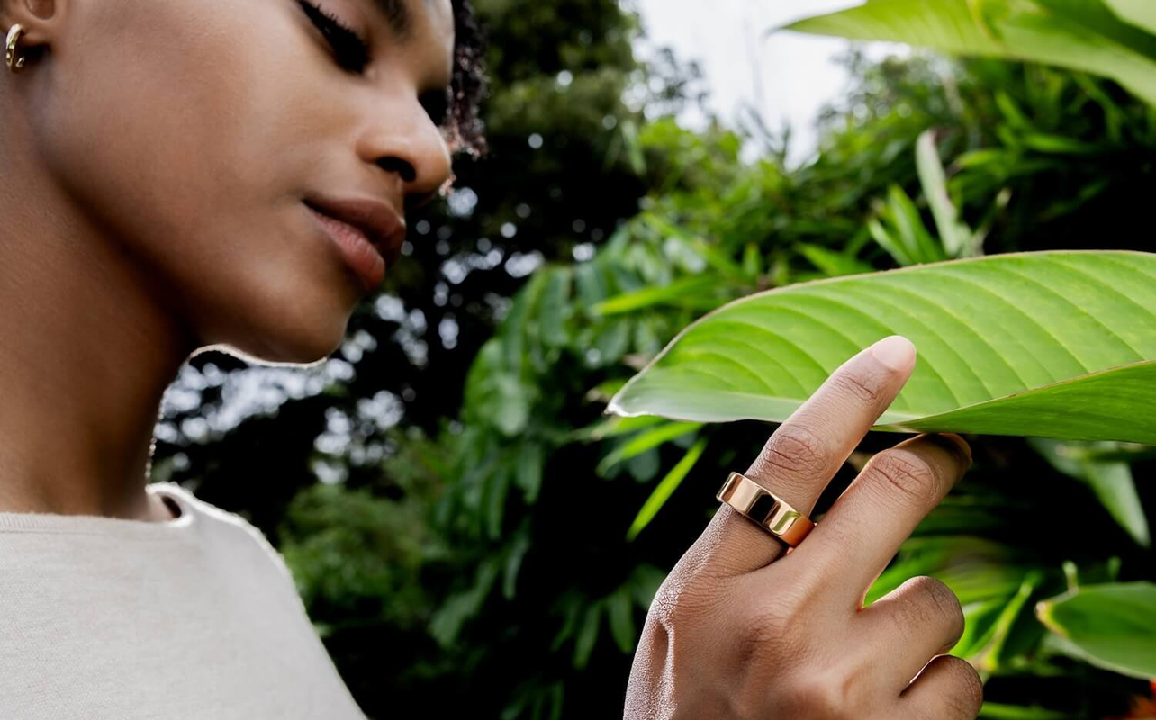 A woman wearing the Ultrahuman Ring Air touching a plant.