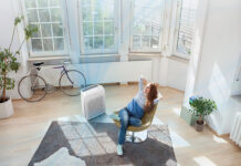 An overhead view of a woman in a living room with a Winix air purifier.