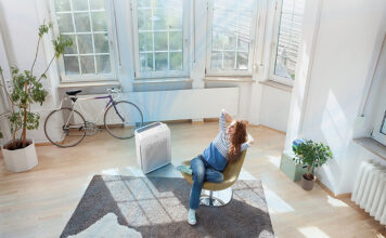 An overhead view of a woman in a living room with a Winix air purifier.