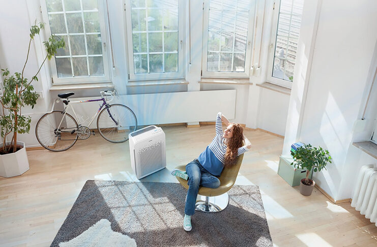 An overhead view of a woman in a living room with a Winix air purifier.