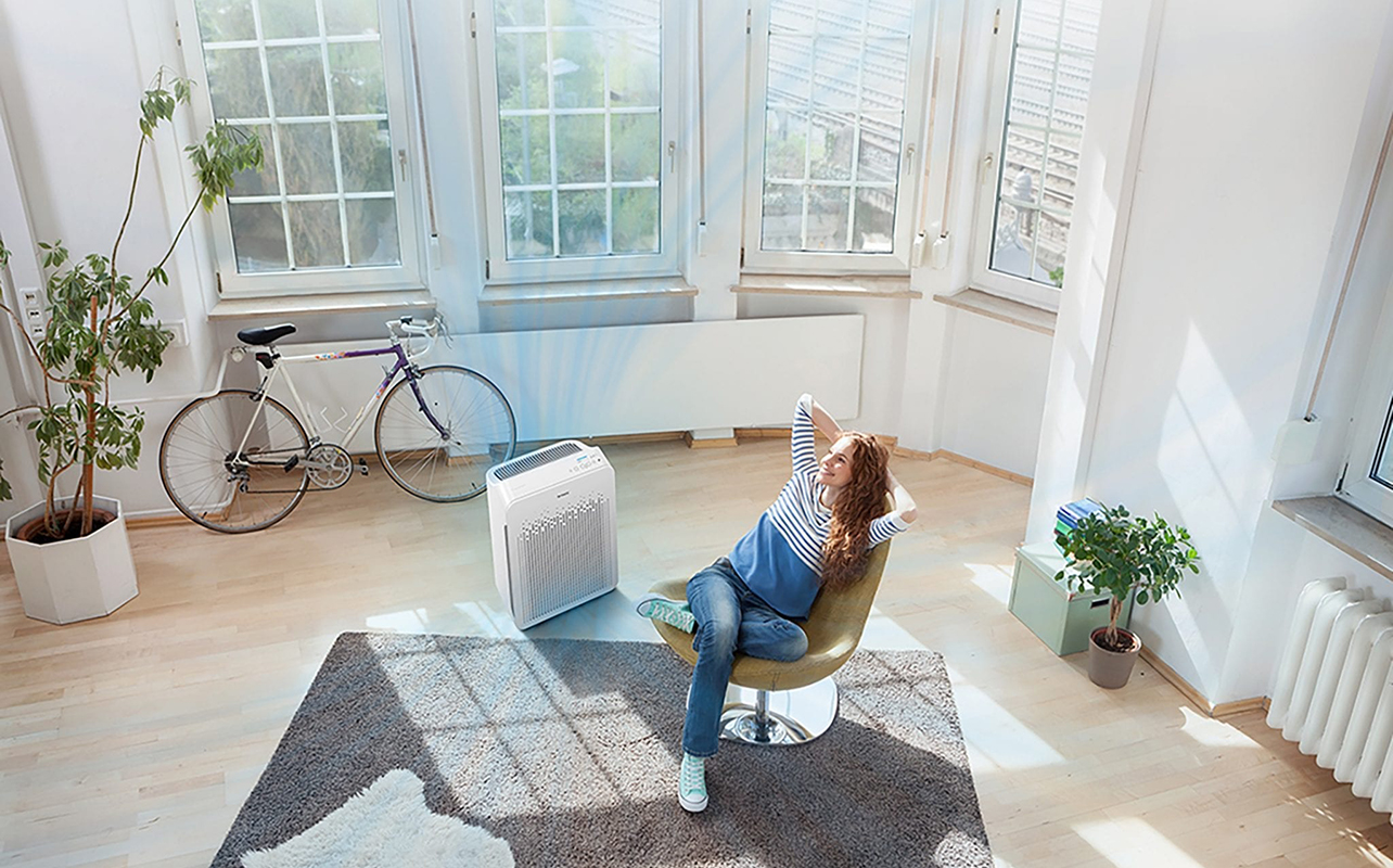 An overhead view of a woman in a living room with a Winix air purifier.