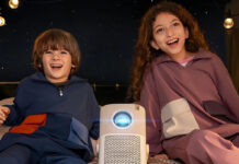 Two kids in a tent outside with a Yaber T2 projector between them.