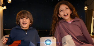 Two kids in a tent outside with a Yaber T2 projector between them.
