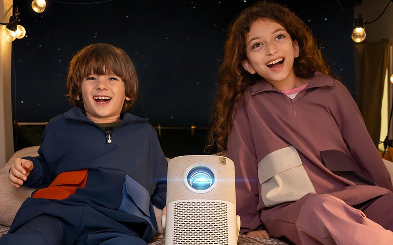 Two kids in a tent outside with a Yaber T2 projector between them.