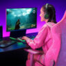 Woman playing a video game on a monitor wearing headphones.