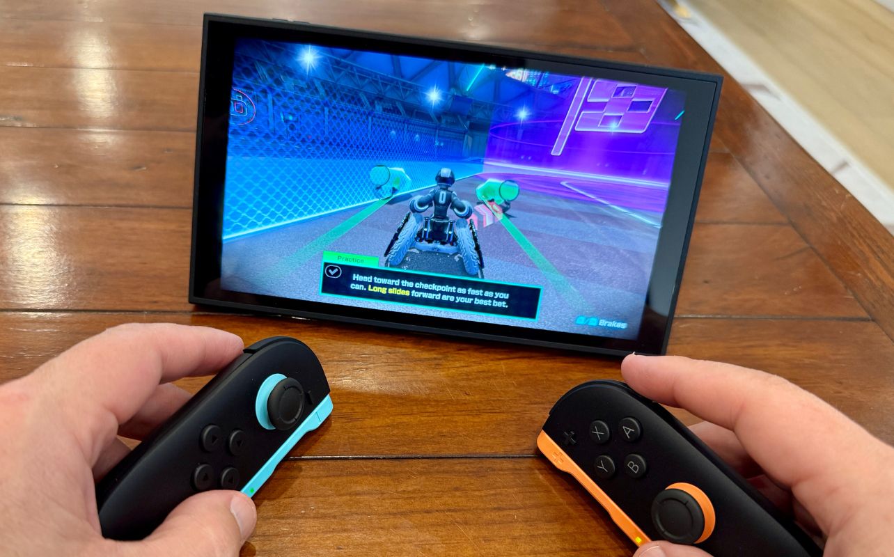 Hands holding gaming controllers playing a racing game on a tablet. Here's how to use mouse mode with Joy Con 2