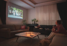 Woman watching home cinema projection with her dog in the living room at home.