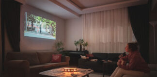 Woman watching home cinema projection with her dog in the living room at home.