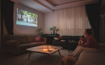Woman watching home cinema projection with her dog in the living room at home.