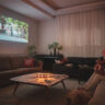 Woman watching home cinema projection with her dog in the living room at home.