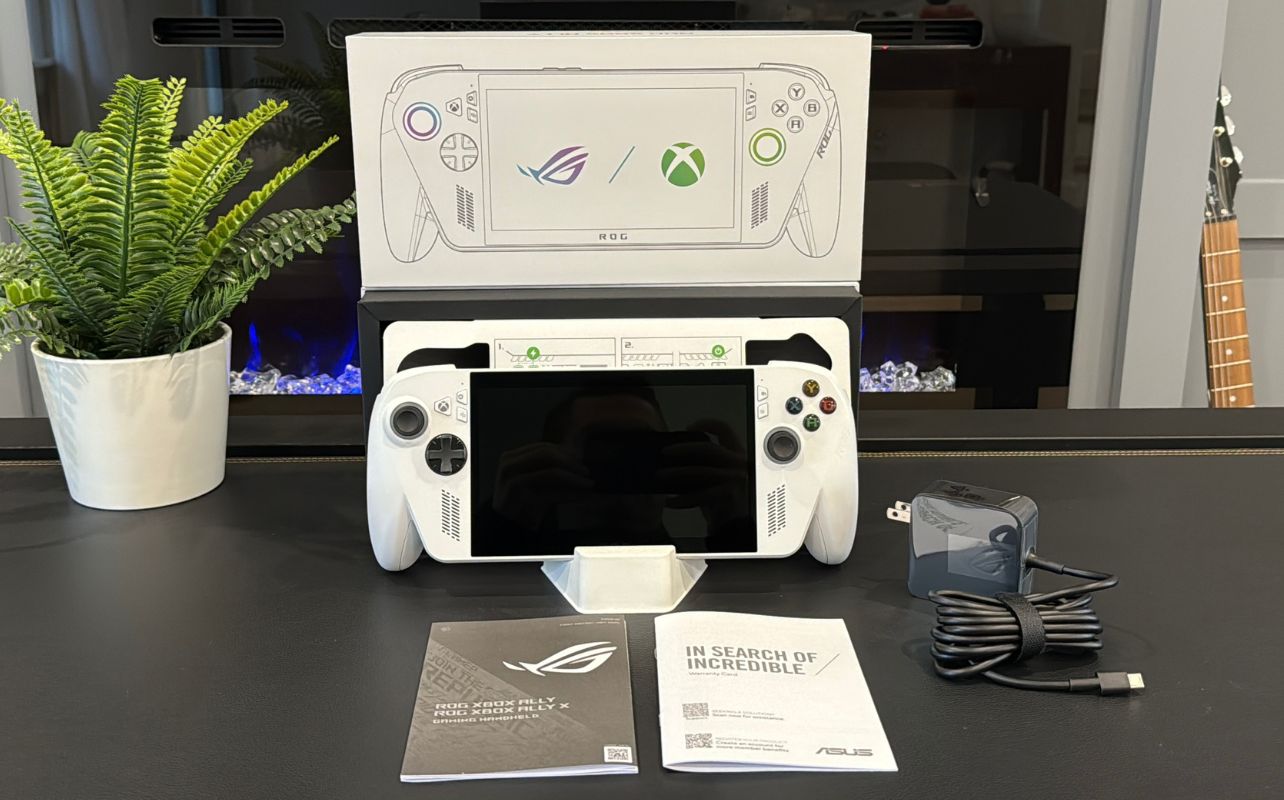 The Xbox Ally X white shell console with all its components on display on a desk.