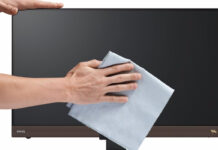 Man's hands wiping dry a computer monitor with a microfibre cloth.