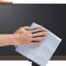 Man's hands wiping dry a computer monitor with a microfibre cloth.