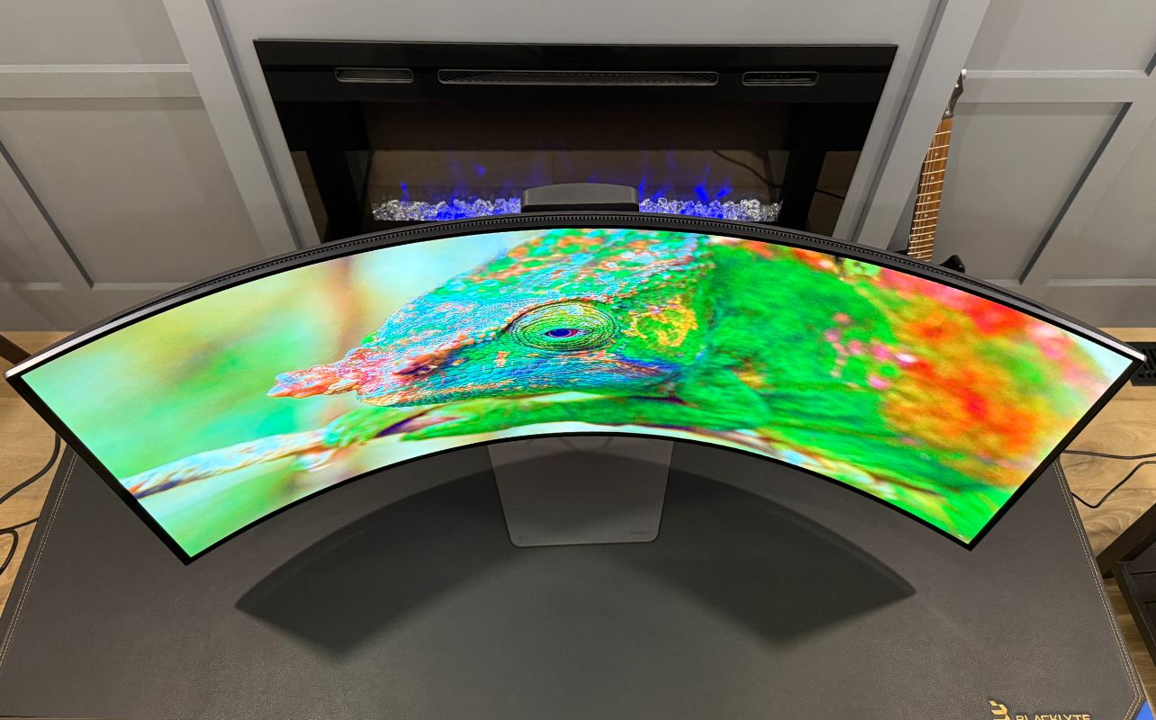 Curved LG UltraGear 5K2K monitor displays a vibrant image of a colourful chameleon.