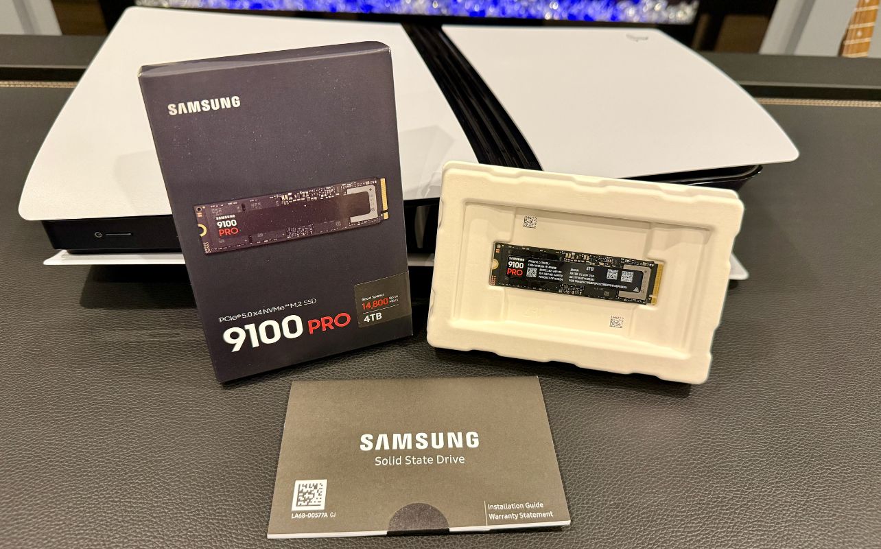 The Samsung 9100 Pro SSD in front of the PS5 Pro gaming console is unboxed with manuals.