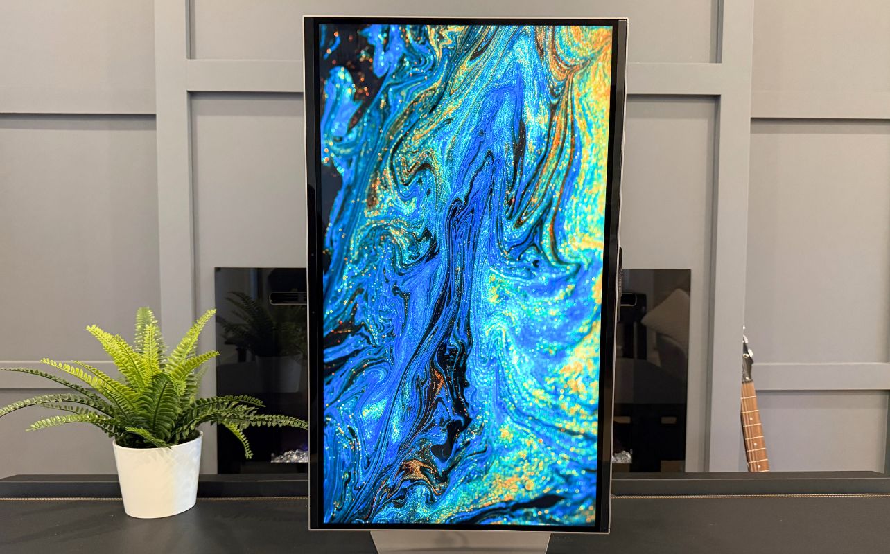 Samsung Odyssey 3D monitor in vertical monitor displays vibrant abstract blue and gold swirls.