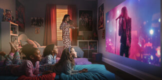 Two kids lying on a bed watching a movie on a projector screen using an Epson projector.