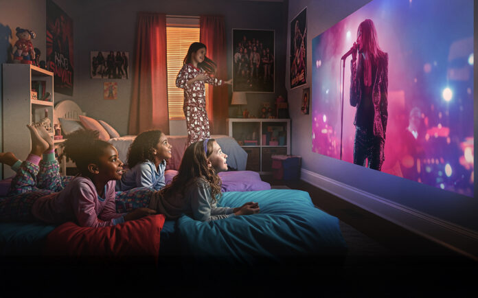 The ultimate projector experience: Inside Epson’s new Lifestudio series Two kids lying on a bed watching a movie on a projector screen using an Epson projector.
