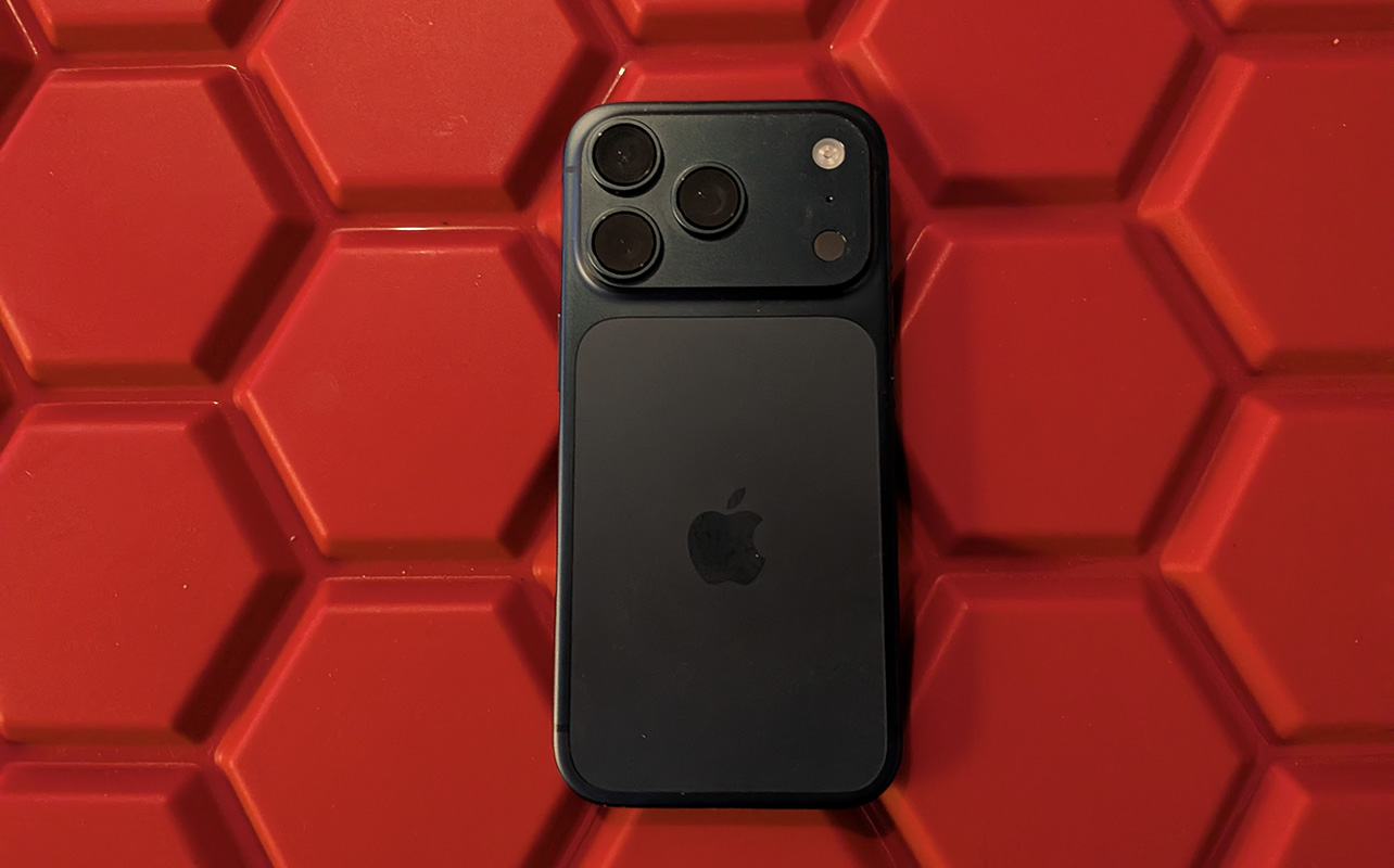 The back of an iPhone 17 Pro atop a red hexagonal background.