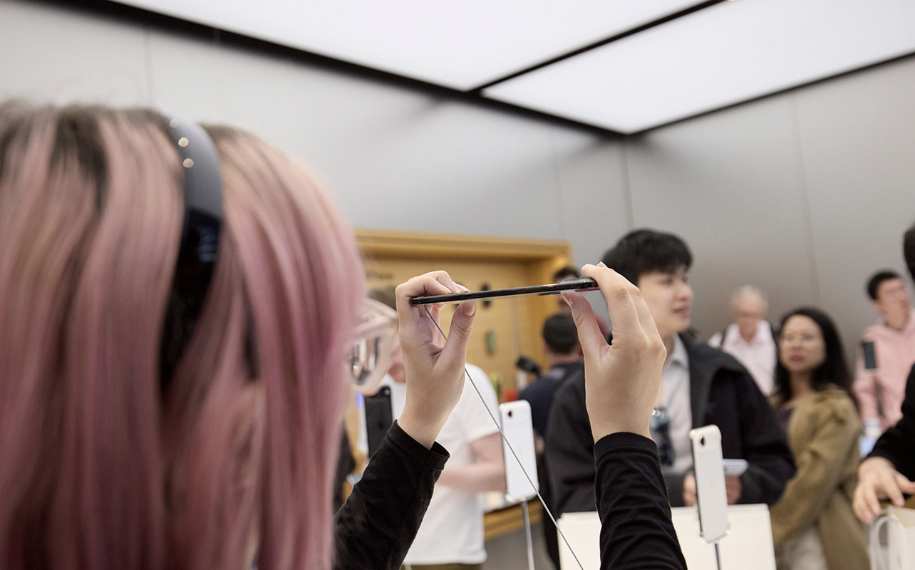 A woman holding the iPhone Air on its side in an Apple Store.