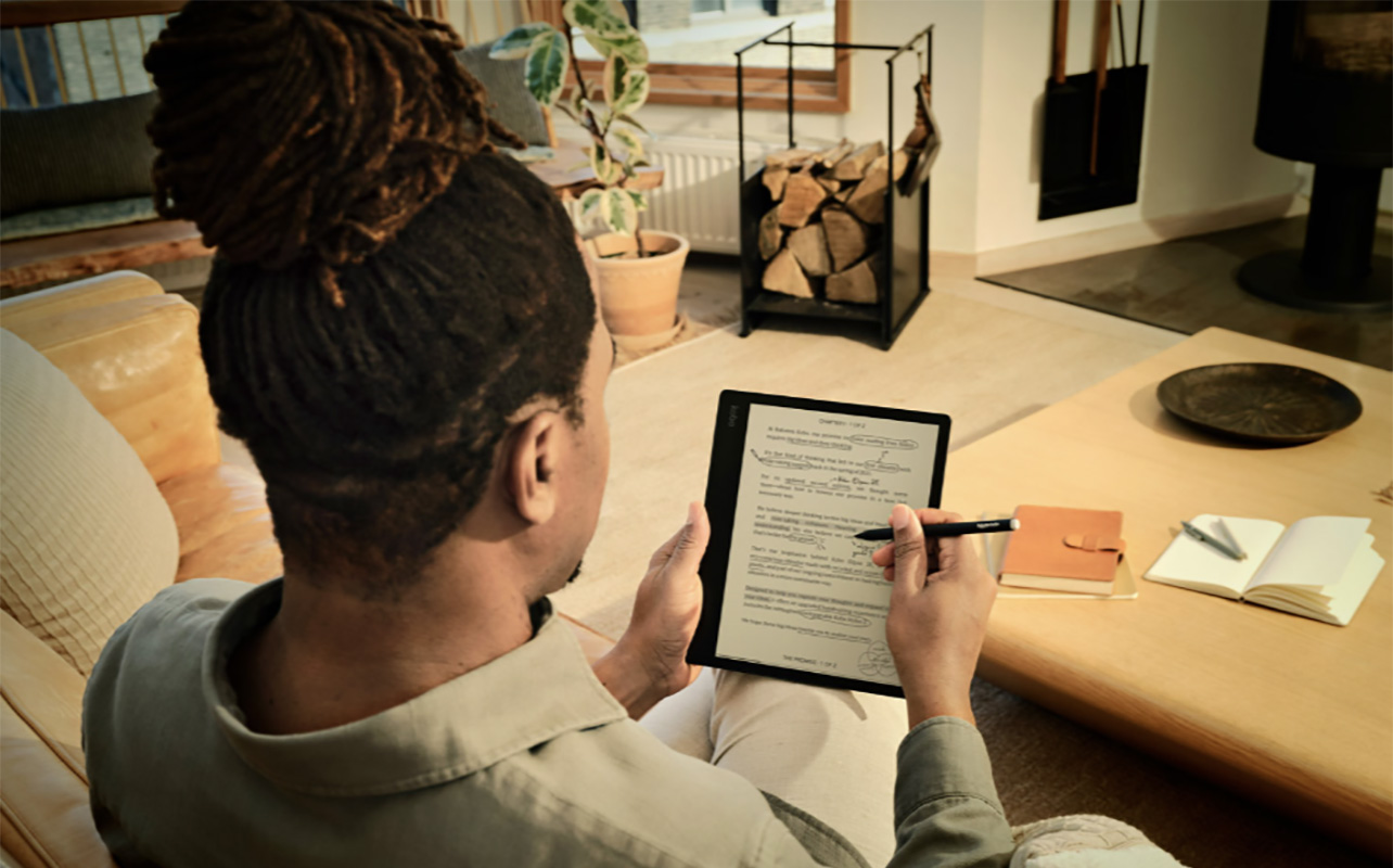 The back of a man writing notes on a Kobo Elipsa 2E eReader with a stylus.