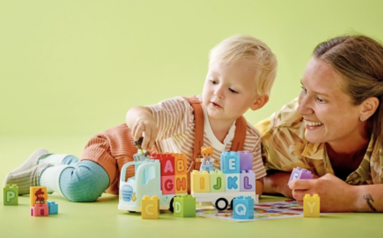A mom playing with a toddler with an LEGO Duplo Alphabet Truck.