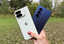 A hand holding the Google Pixel 10 Pro Fold and Samsung Galaxy Z Fold 7 outside.