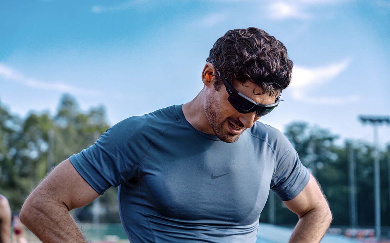 A man wearing the Powerbeats Fit while taking a pause from running.