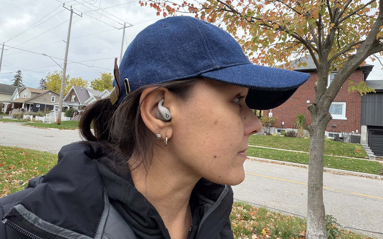 A woman wearing the Powerbeats Fit earbuds while outside.