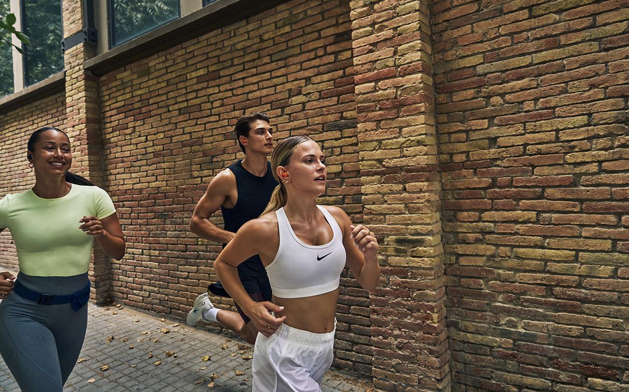 Three people running while wearing the Powerbeats Fit earbuds.