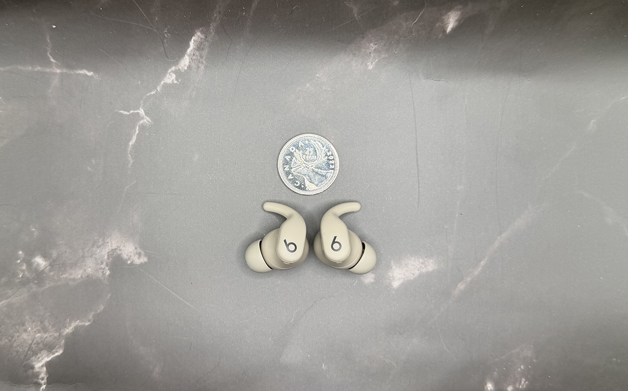 Powerbeats Fit beside a quarter for scale.