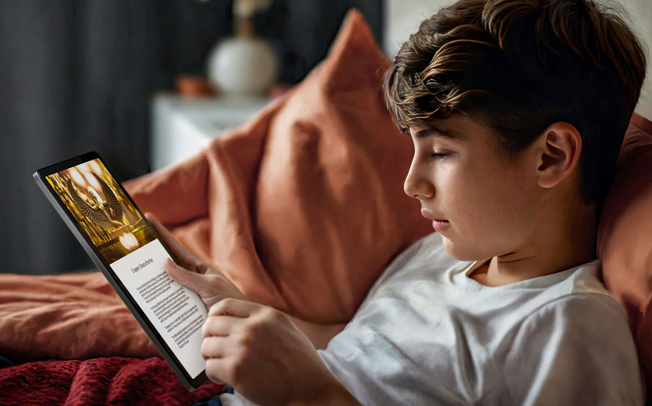 Boy reading tablet in bed