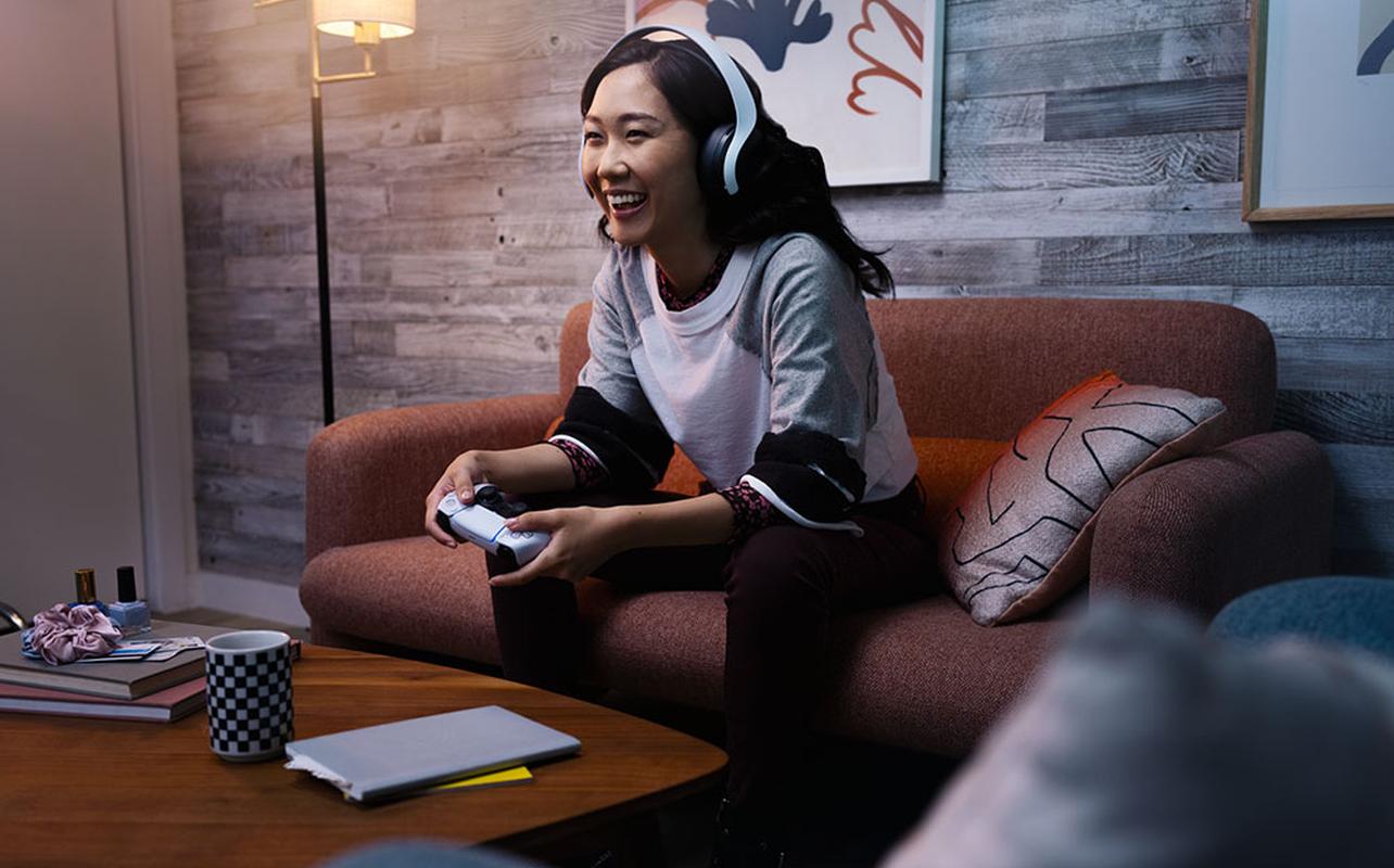 Une joueuse utilise le casque de jeu sans fil PlayStation PULSE Elite pour jouer à des jeux vidéo avec des amis.