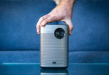 Hand placed on top of XGIMI Halo+ portable projector in front of couch.