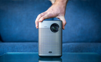 Hand placed on top of XGIMI Halo+ portable projector in front of couch.