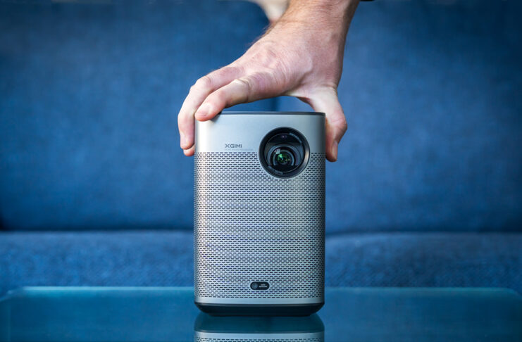 Hand placed on top of XGIMI Halo+ portable projector in front of couch.