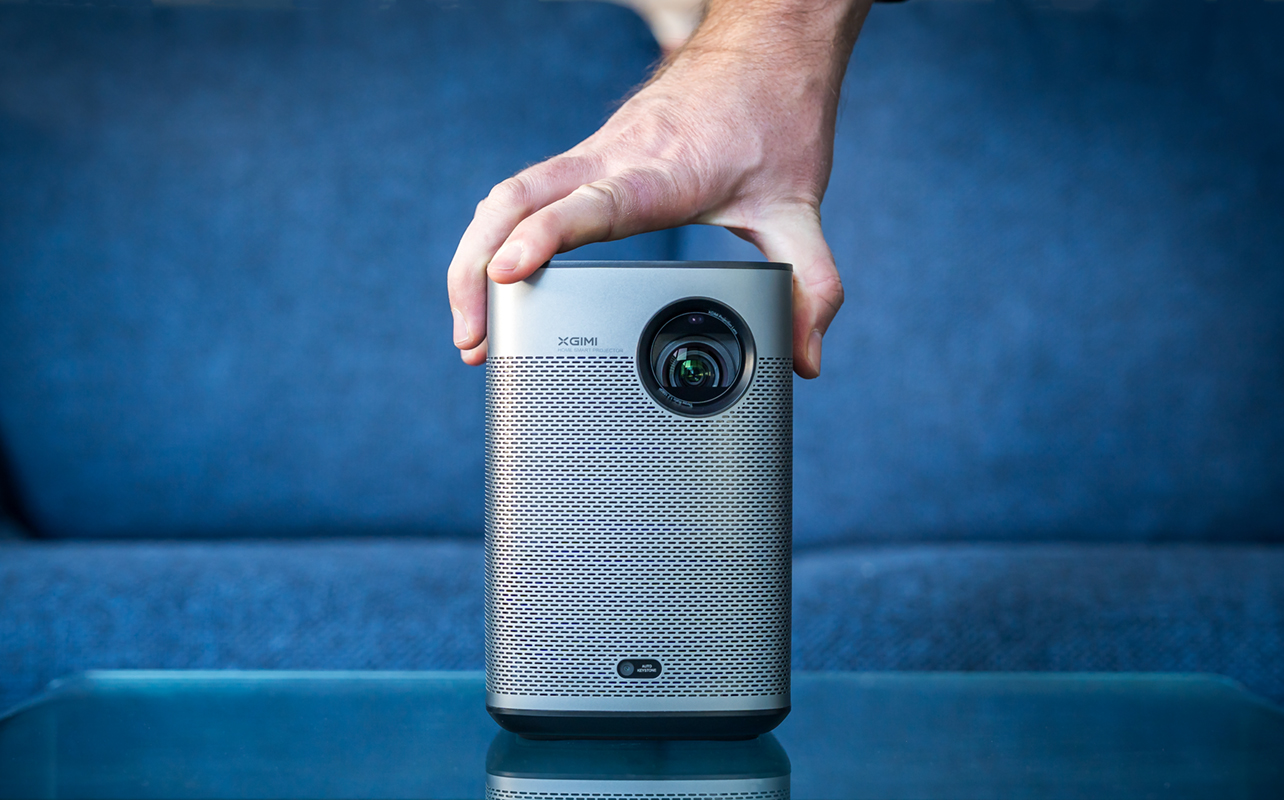 Hand placed on top of XGIMI Halo+ portable projector in front of couch.