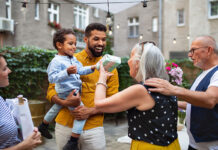 Cheerful senior woman getting birthday gift from her small grandson outdoors in front or back yard.