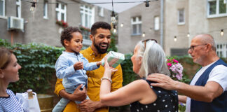Cheerful senior woman getting birthday gift from her small grandson outdoors in front or back yard.