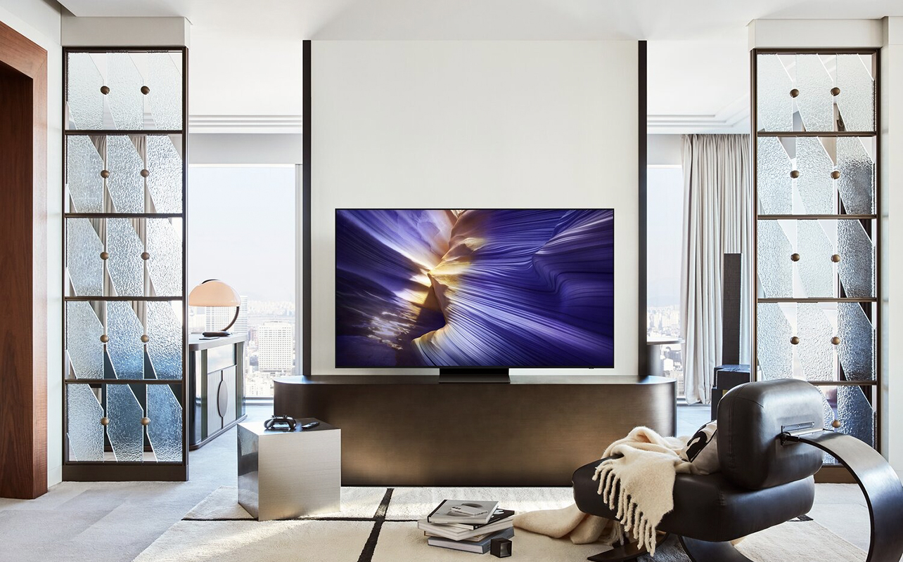 A Samsung S90F OLED TV mounted on a stand in a living room.