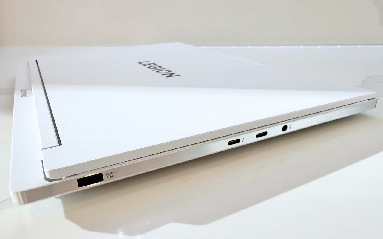 The white Lenovo Legion 7i laptop sits on top of a marble counter, showing off its display ports.