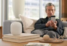 A man sitting on the couch with a Nest Wi-Fi router in front of him.